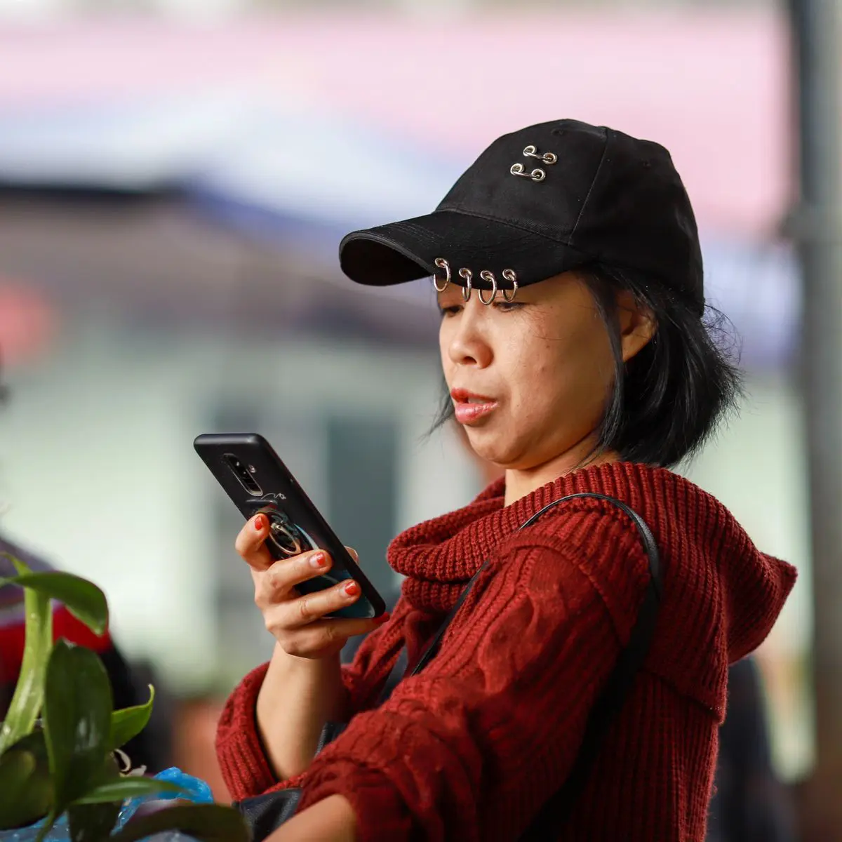 Une femme utilise son smartphone, geste illustrant les premiers réflexes de mise en sécurité